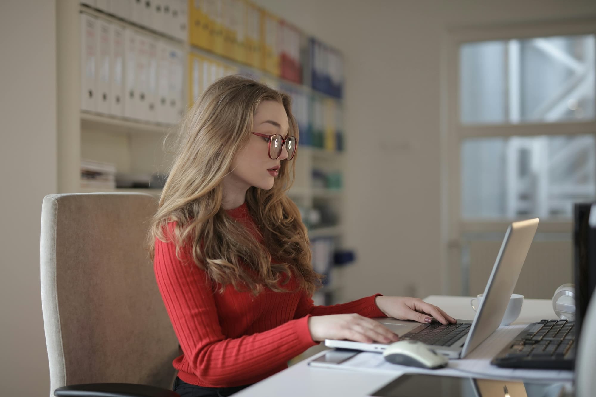 Young woman at desk typing on laptop.